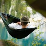 a man sitting in a hammock with a view of a lake