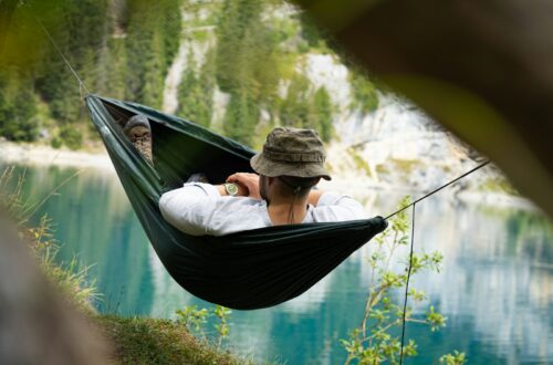 a man sitting in a hammock with a view of a lake
