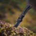 a black knife sitting on top of a moss covered tree