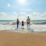 man, woman and child holding hands on seashore