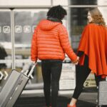 Man in Red Coat and Woman in Red Poncho Holding Hands and Suitcases