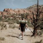 Man backpacker walking in mountainous terrain