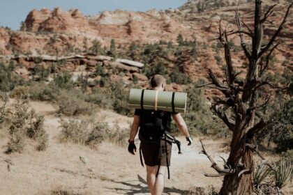 Man backpacker walking in mountainous terrain