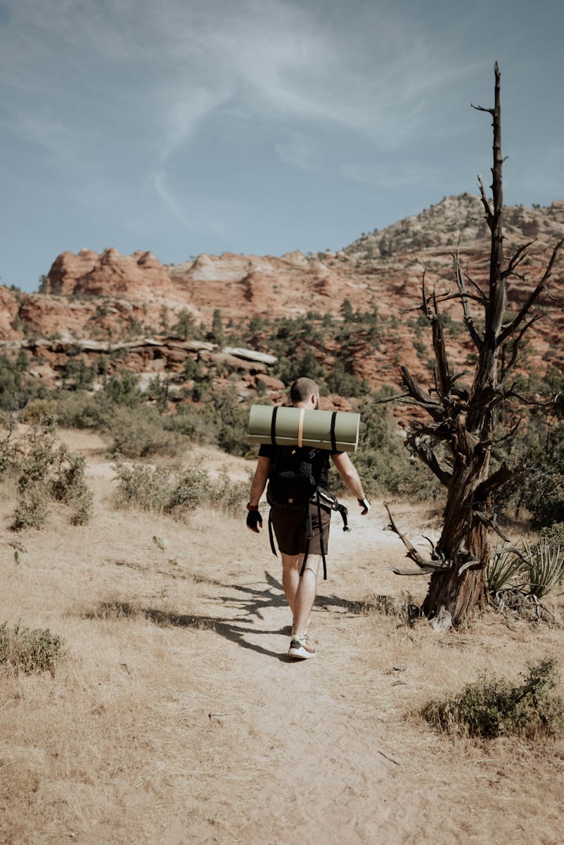 Man backpacker walking in mountainous terrain