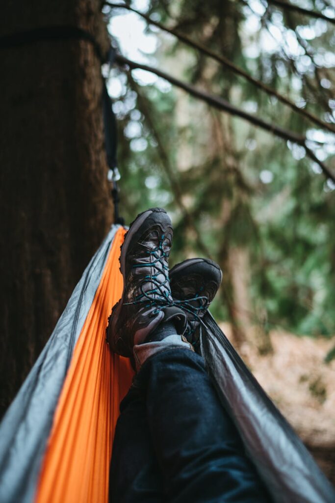 Person Wearing Pair of Black Hiking Shoes Lying on Orange and Gray Hammock