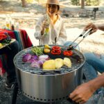 a man and a woman cooking food on a grill