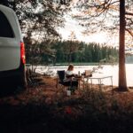 a van parked next to a lake with a person sitting at a table