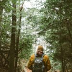 person with backpack walking through woods